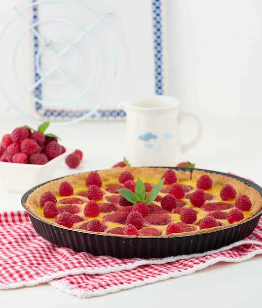 Round quiche with red strawberries and raspberries on a white table