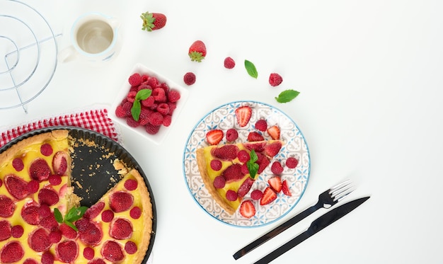 Round quiche with red strawberries and raspberries on a white table