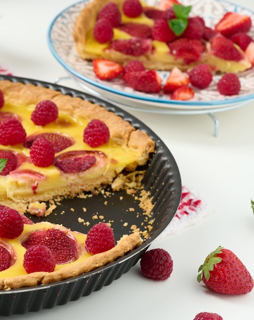 Round quiche with red strawberries and raspberries on a white table