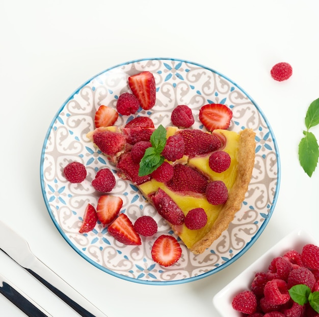 Round quiche with red strawberries and raspberries on a white table