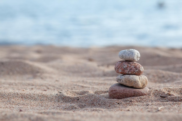 Round stones lie on top of each other in a column on the seashore on a sunny summer day