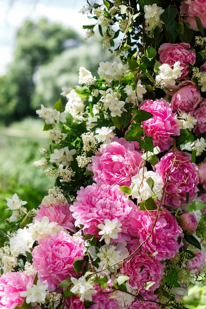 Round swing of wooden branches, decorated with a lot of peonies and roses, tulle. Spring wedding floristics in white and pink tones, tender photozone