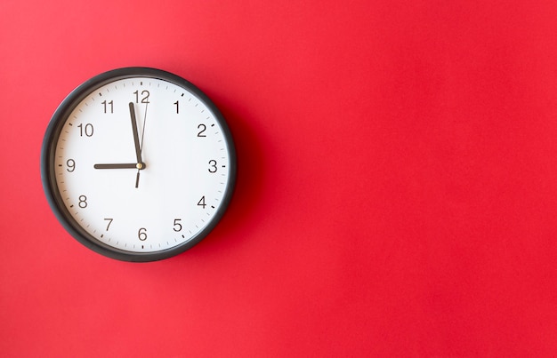 Round wall clock on red surface showing 9