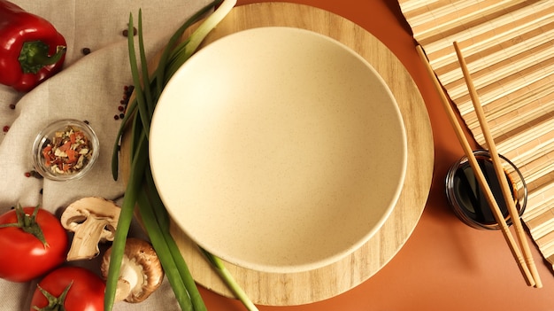 Round wooden board and plate, sauce and various vegetables on the table,