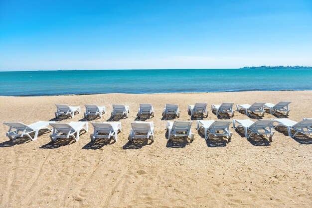 Row of beach chairs on the beach with yellow sand near blue sea