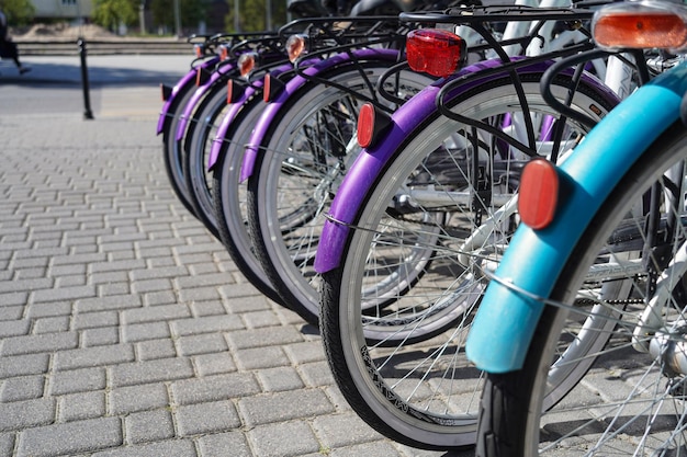 A row of bicycles wheels for rent standing in the street