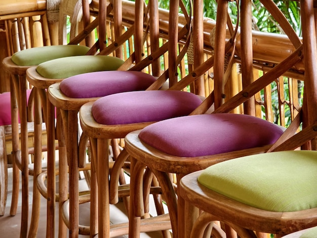 Photo a row of chairs made of wood with cushions in purple and green colors