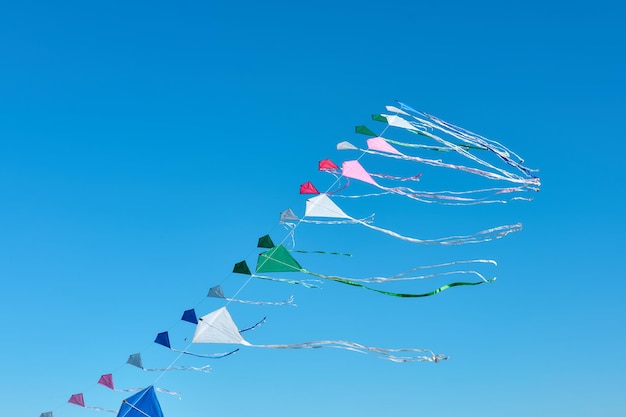 Row of colorful kites flying in the blue sky