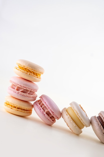 Row of colorful pastel french macaroons or macarons  on white and pink background