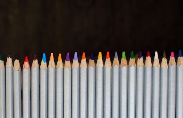 Row of colorful pencils on black background Art design Drawing concept Pencils with copy space