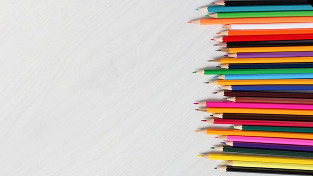 Row of colorful pencils on white wooden background top view Education concept