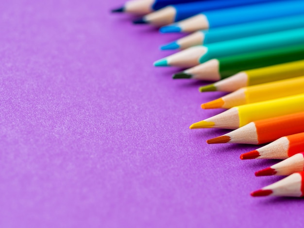 Row of colorful watercolor pencils on lilac. 