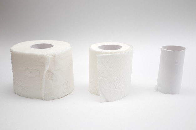 Row of full toilet paper and Empty toilet paper rolls on white background.