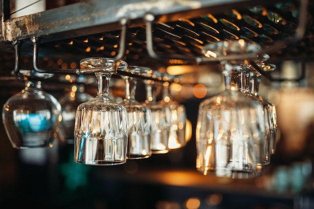 Row of glasses hanging on the bar counter closeup