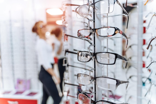 Row of glasses at an opticians Eyeglasses shop Stand with glasses in the store of optics Woman chooses spectacles Eyesight correction