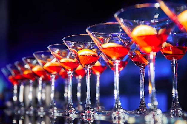 A row of glasses with alcoholic drink and orange slices on the bar counter