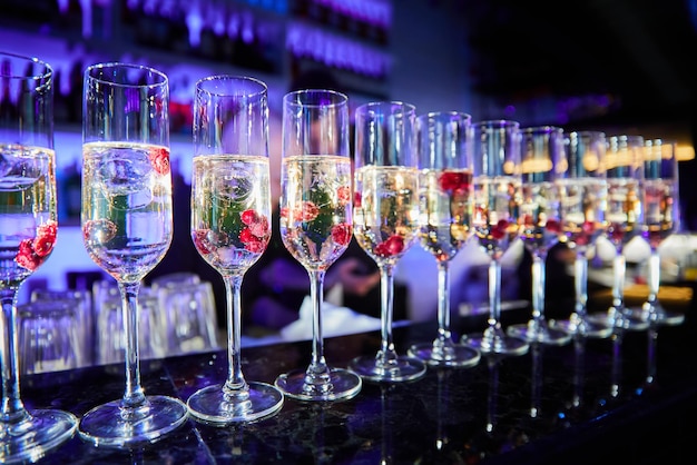 Row of glasses with cherries and champagne on the bar counter in the process of preparing cocktails