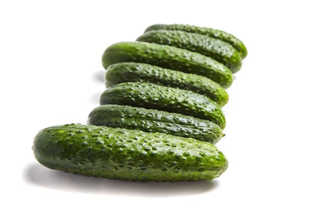 Row green cucumbers isolated on white background