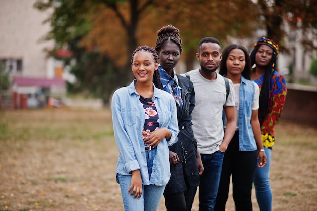 Row of group five african college students spending time together on campus at university yard Black afro friends studying Education theme