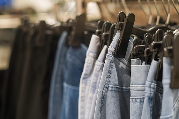 Row of jeans on the hanger in the shop selective focus Concept of buy sale and denim fashion