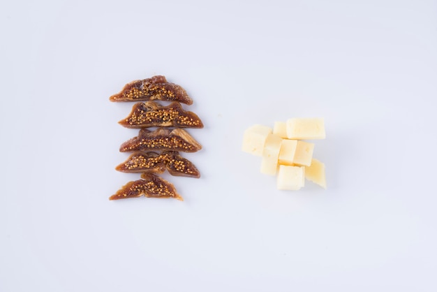 Row of pieces of tasty dried fig and pile of pieces of pecorino cheese on white background