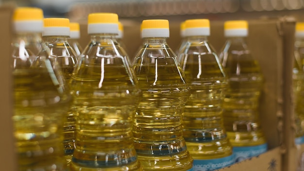 Row of plastic bottles of sunflower or olive oil in a store Closeup selective focus