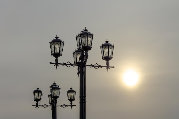 A row of street lights with the sun behind them