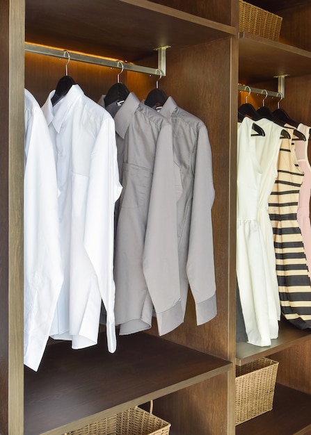 Row of white and gray shirts  hanging in wooden wardrobe