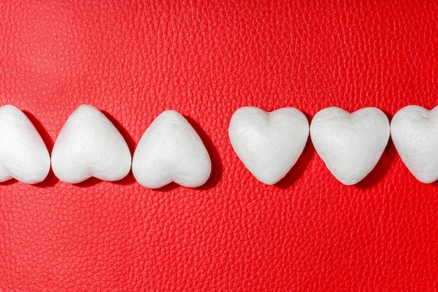 Row of white hearts on red leather background