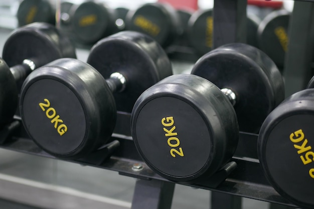 Rows of black color dumbbells with numbers in the gym