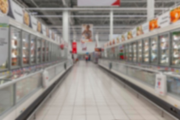 Rows of frozen food refrigeration units in a supermarket Blurred