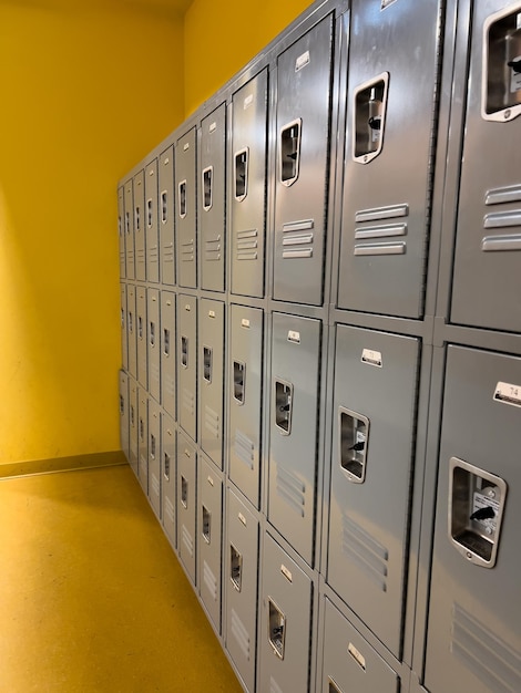 Rows of gray school lockers lined up against a yellow wall