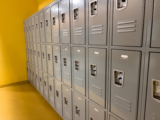 Rows of gray school lockers lined up against a yellow wall