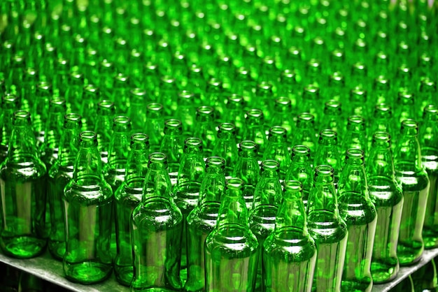 Rows of new empty green glass bottles. on the production line.