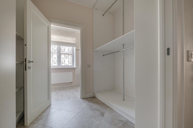 Rows of shelves and clothes hangers in empty big wardrobe room in modern apartment or hotel