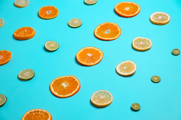 Rows of sliced lemons limes and orange fruits set on blue background