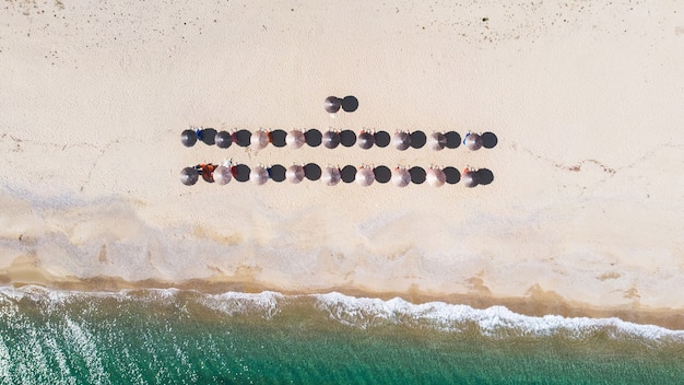 Rows of umbrellas made of reed with sunbeds under them on the beach