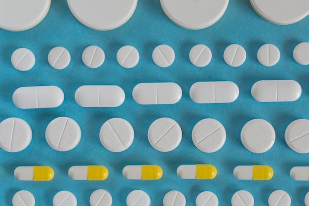 Rows of white pills or tablets on the blue backgroun