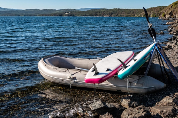 Photo rubber boat with two sup boards on a rocky seashore