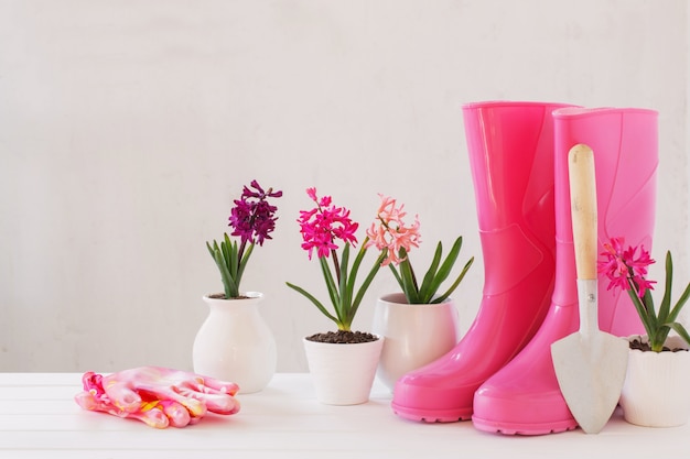 Rubber boots and spring flowers on white wall