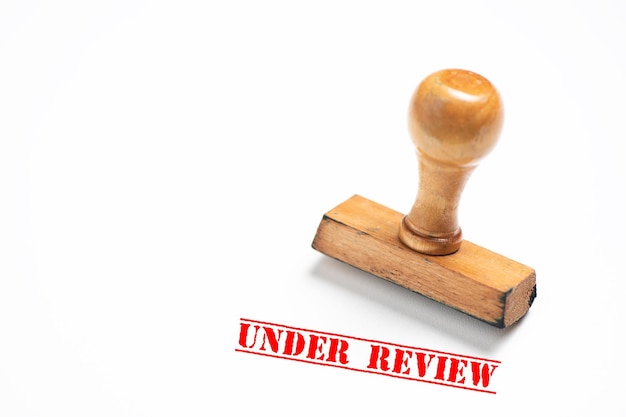 Rubber stamp with under review sign on white background. Close up