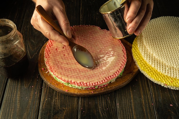 Rubbing condensed milk with a spoon over the faffle circles while preparing the cake by the chef hands