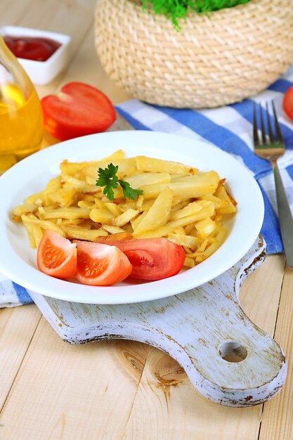 Ruddy fried potatoes on plate on wooden table closeup