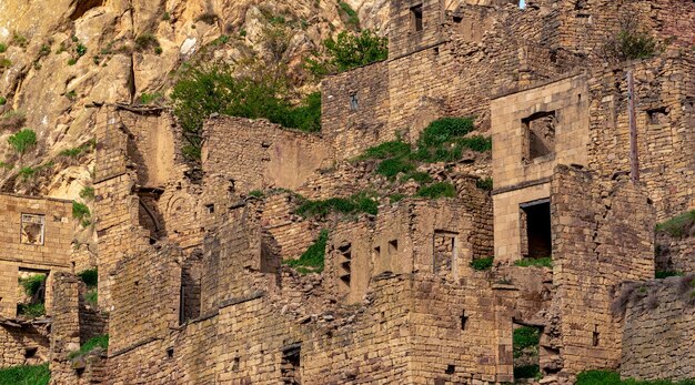 Ruins of stone houses attached to the rock in the depopulated village of Gamsutl in the sunset rays