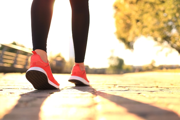 Runner feet running on road closeup on shoe, outdoor at sunset or sunrise.