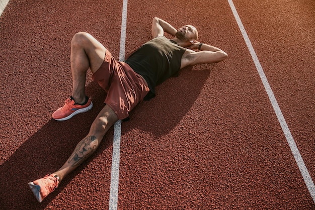 Runner lying on the track resting after workout