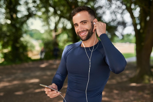 Photo runner man and phone with music in portrait at park smile and exercise with audio streaming app person happy and smartphone with online subscription to listen to playlist at training in seattle