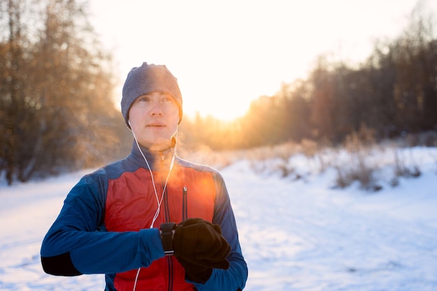 Runner wearing warm sporty clothes in headphones looks at a modern smart clock