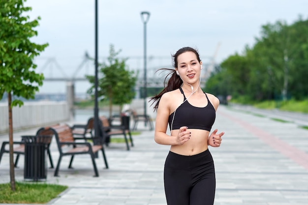 Running asian woman on the waterfront Morning jogging The athlete trains