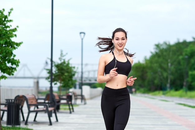 Running asian woman on the waterfront Morning jogging The athlete trains